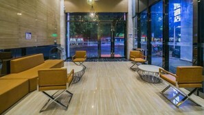 Vestíbulo de hotel con recepción, zona de estar y grandes ventanales con vistas a la calle.