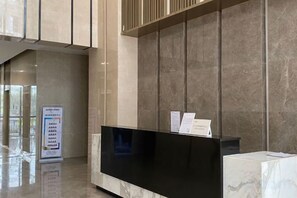 A reception desk with a flat-screen TV, a marble counter, and a wall-mounted sign. - Light Time Hotel (Nanning Greenland Central Plaza) (Nanning)