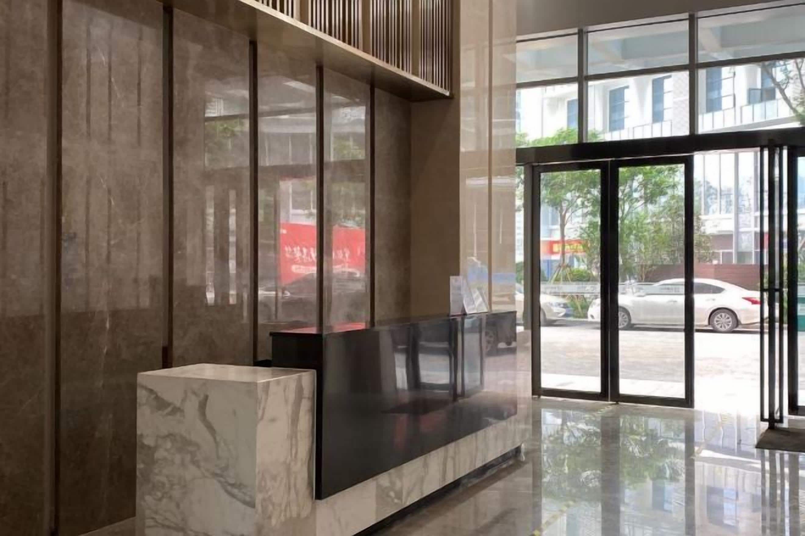 A reception area with a marble reception desk, large glass doors, and a view of the street outside.