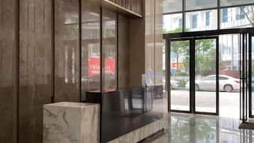 A reception area with a marble reception desk, large glass doors, and a view of the street outside.