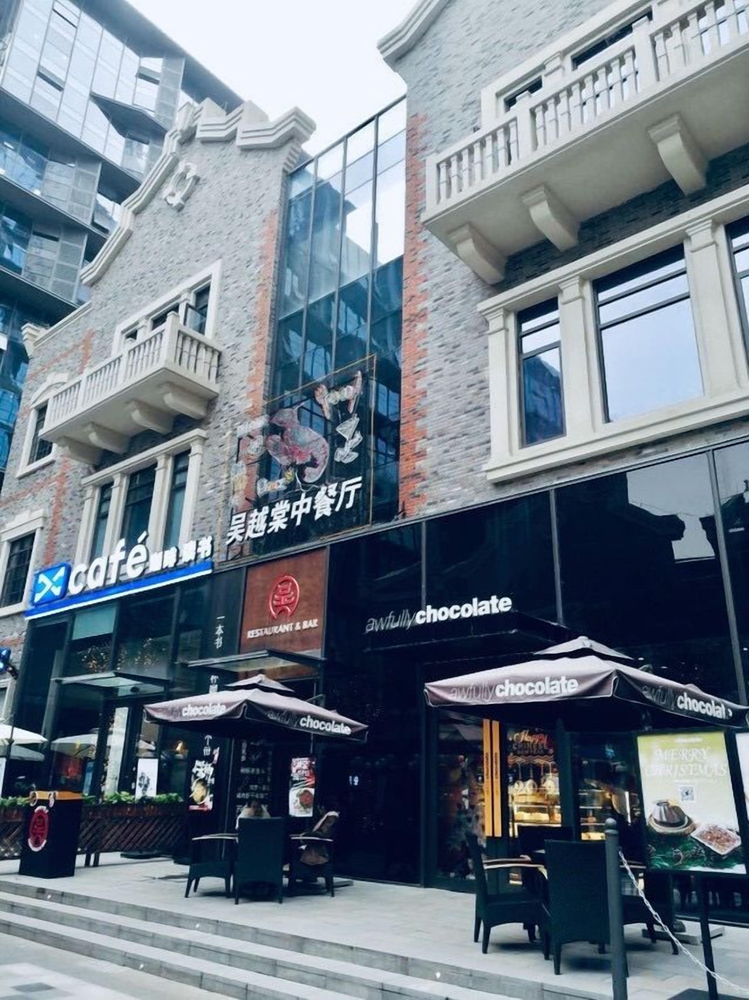 Un edificio con una cafetería y una tienda de chocolates en la planta baja.