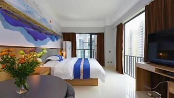 Ein Hotelzimmer mit Bett, Fernseher, Balkon und einem Gemälde an der Wand.