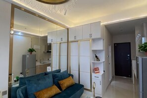A modern living room with a sofa, a mirrored wardrobe, and a kitchen area. - Light Time Hotel (Nanning Greenland Central Plaza) (Nanning)