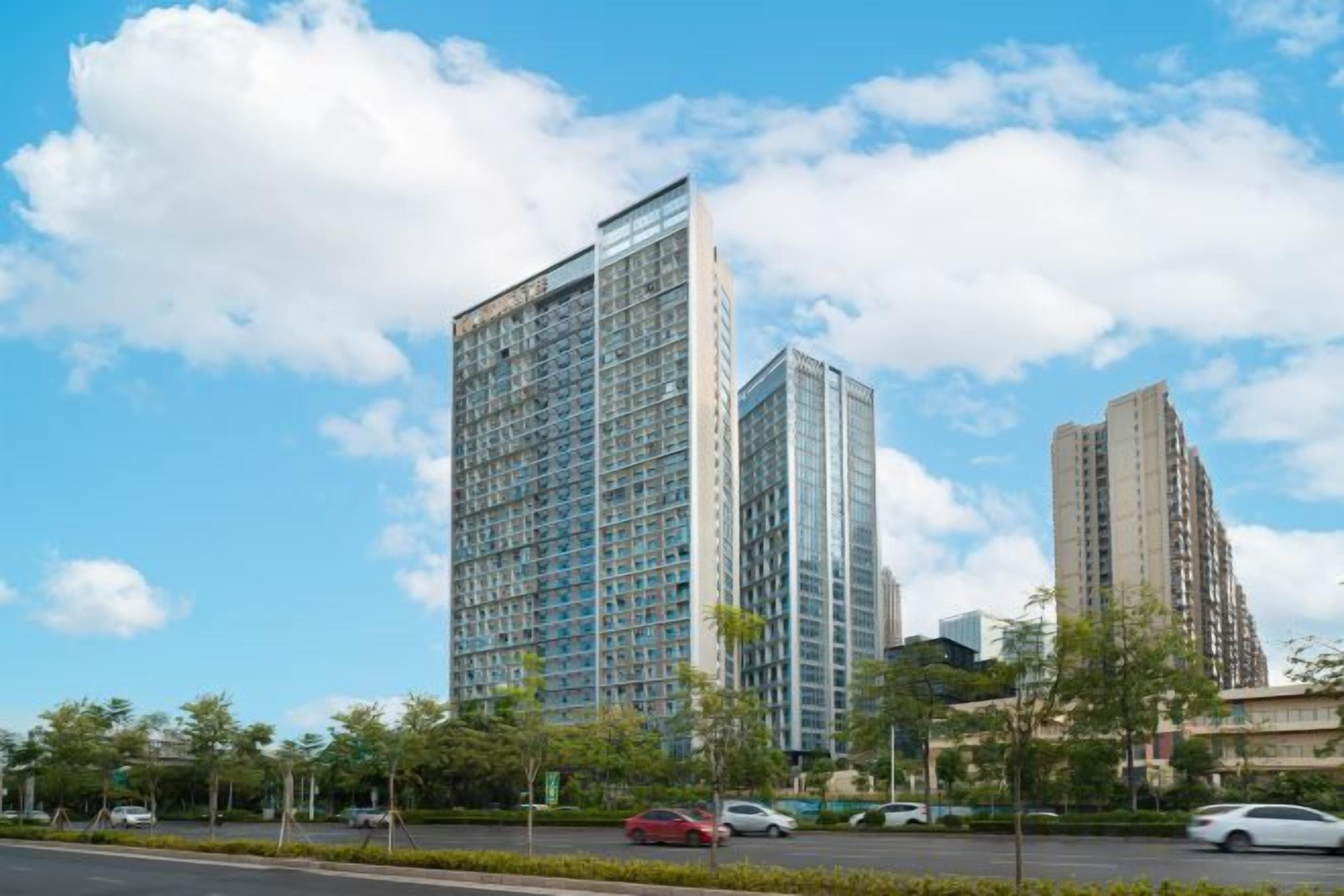 Ein modernes Hochhaus mit Glasfassade, umgeben von einer gepflegten Stadtlandschaft.