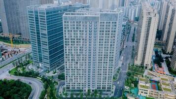 A high-rise building with a grid of windows, surrounded by other tall buildings and a curved road.