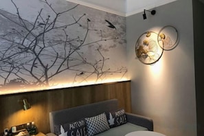 Una habitación de hotel con una cama, una lámpara de pared y una obra de arte en la pared.