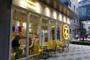 Een restaurant met terras, glazen gevel en neonreclame.