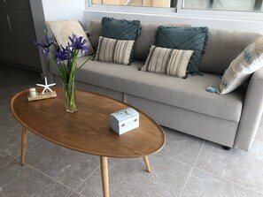 A living room with a wooden coffee table, a vase with flowers, and a sofa with patterned cushions. - Sea front penthouse Porto Petro (Portopetro)