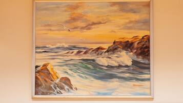 Un cuadro enmarco que muestra una escena costera con olas y rocas.