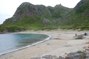 A beach with rocky cliffs and a lighthouse in the background.