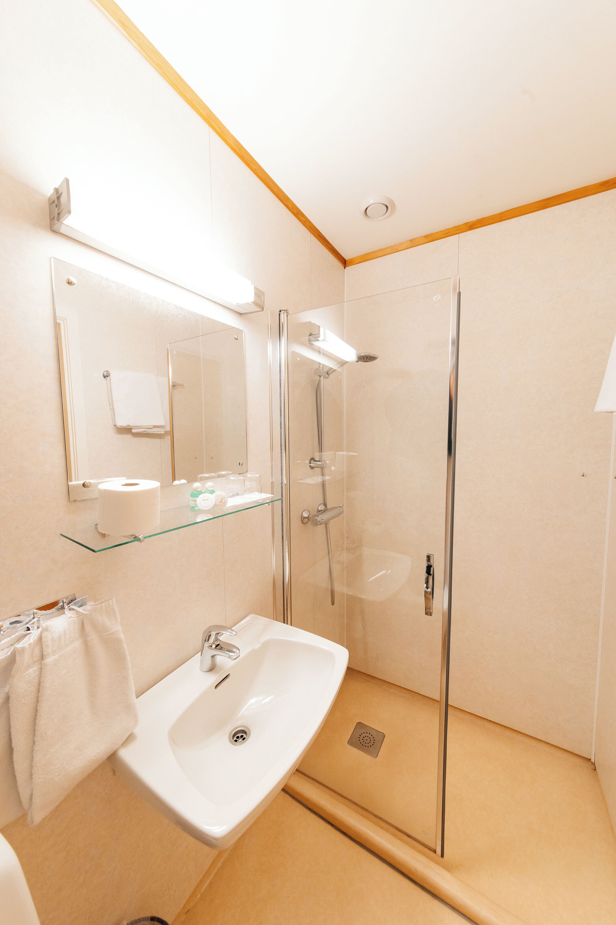 Un baño moderno con cabina de ducha de vidrio, un lavabo blanco y un espejo sobre él.