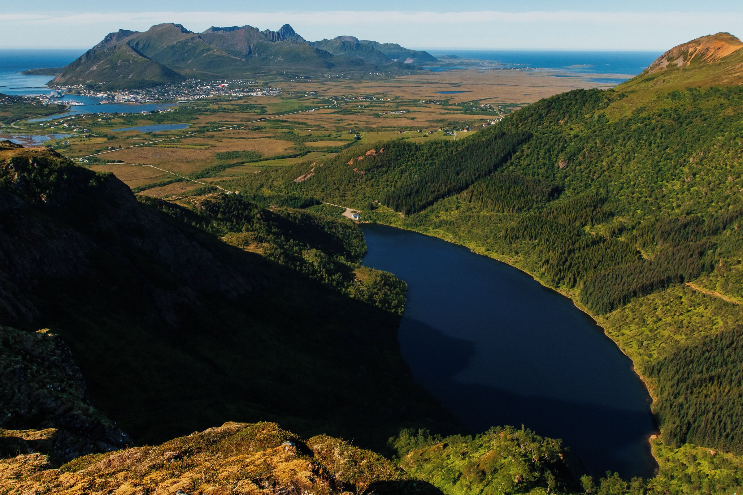 Paisagem montanhosa com um lago e uma cidade no vale.
