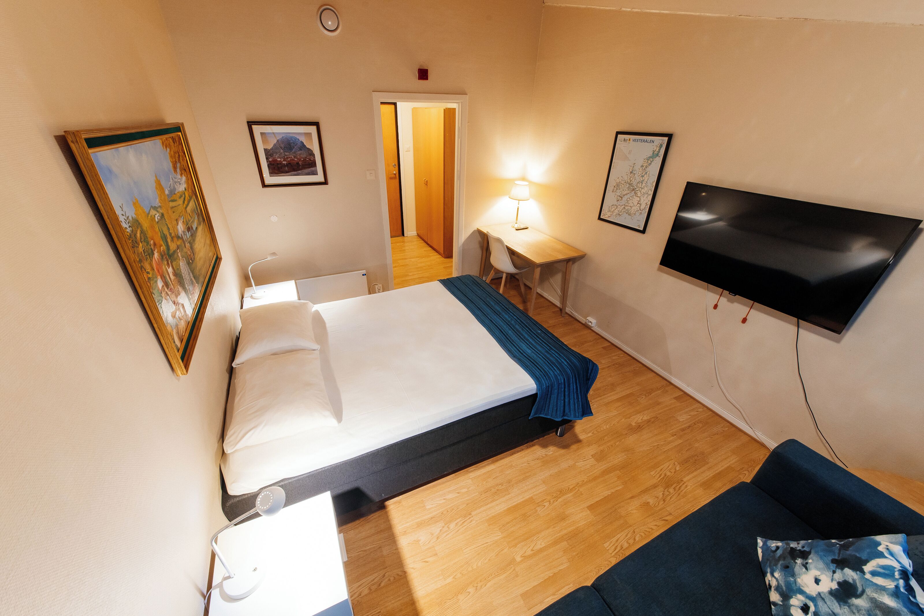 A hotel room with a bed, a desk, a chair, a TV, and a couch.