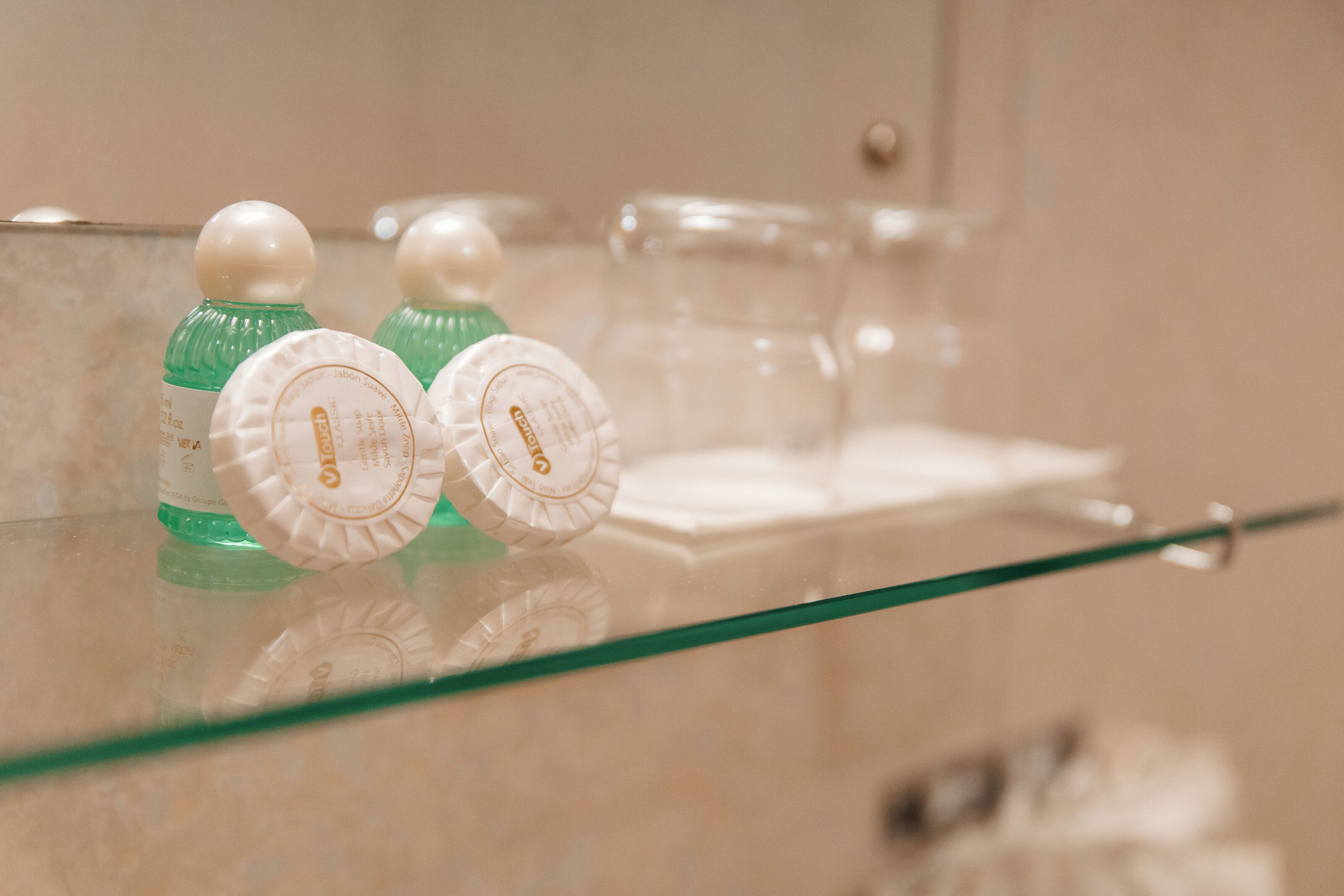 A bathroom with a glass shelf containing toiletries and a mirror.