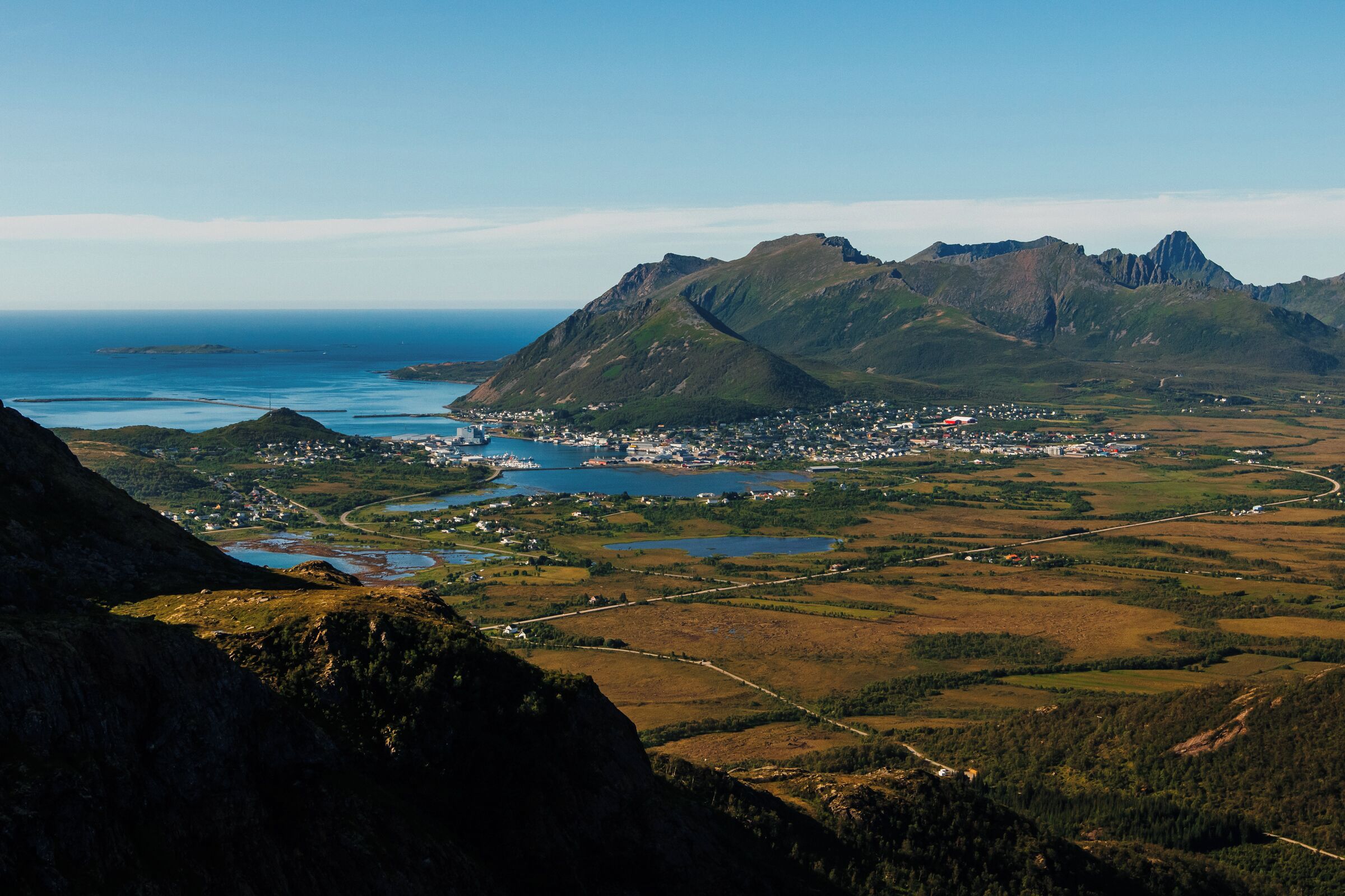 A mountainous landscape with a town and a body of water.