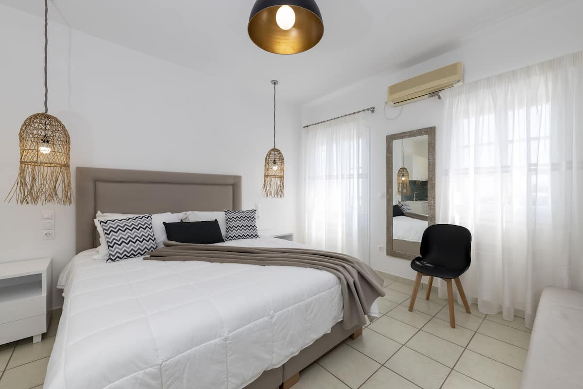 A modern bedroom with a large bed, bedside tables, a chair, and a mirror.