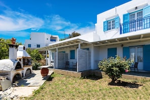 A white building with blue shutters and a covered patio area. - Eutuxia Rooms & Studios (Sifnos)