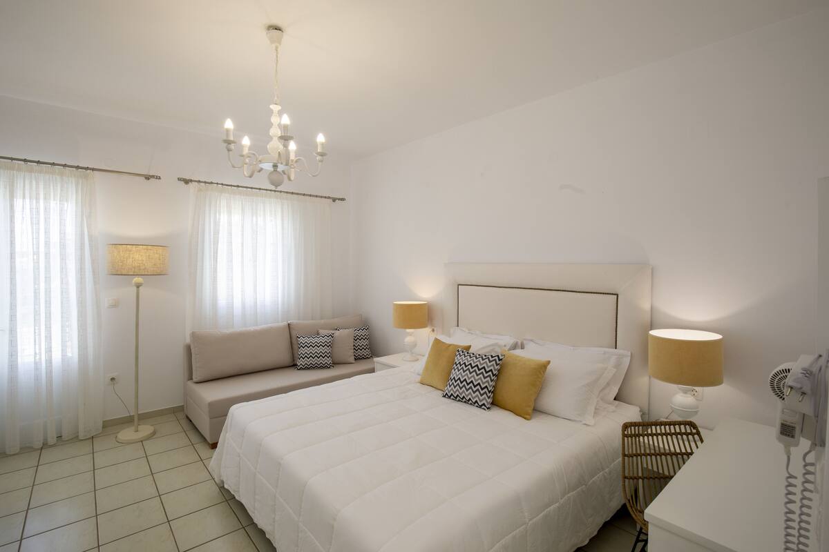 A hotel room with a large bed, a bedside table, a lamp, a chair, and a ceiling light.