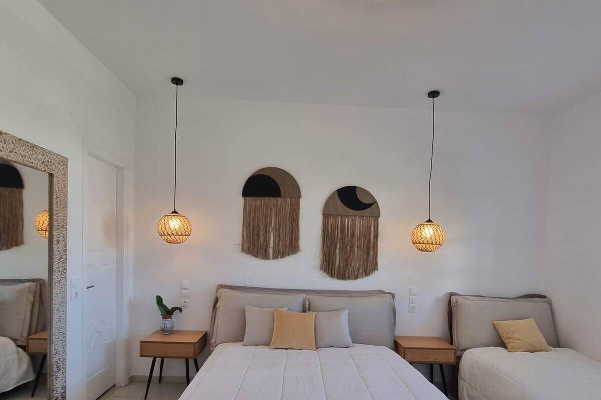 A bedroom with a large bed, two bedside tables, a mirror, and wall-mounted lamps.