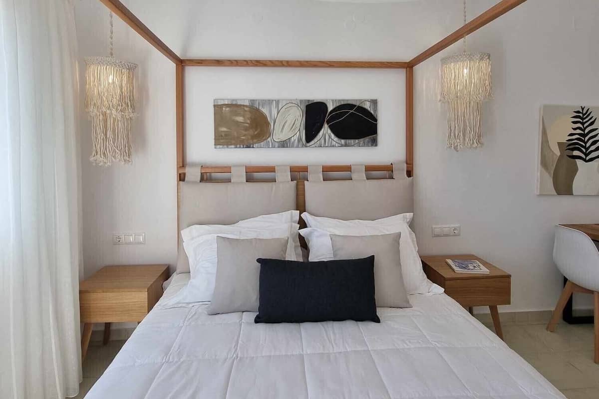 A bedroom with a large bed, wooden headboard, two bedside tables, and a chair.