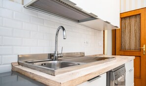 A kitchen with a stainless steel sink, a wooden countertop, and a built-in dishwasher. - Mecenate Apartment Cavour (Rome)