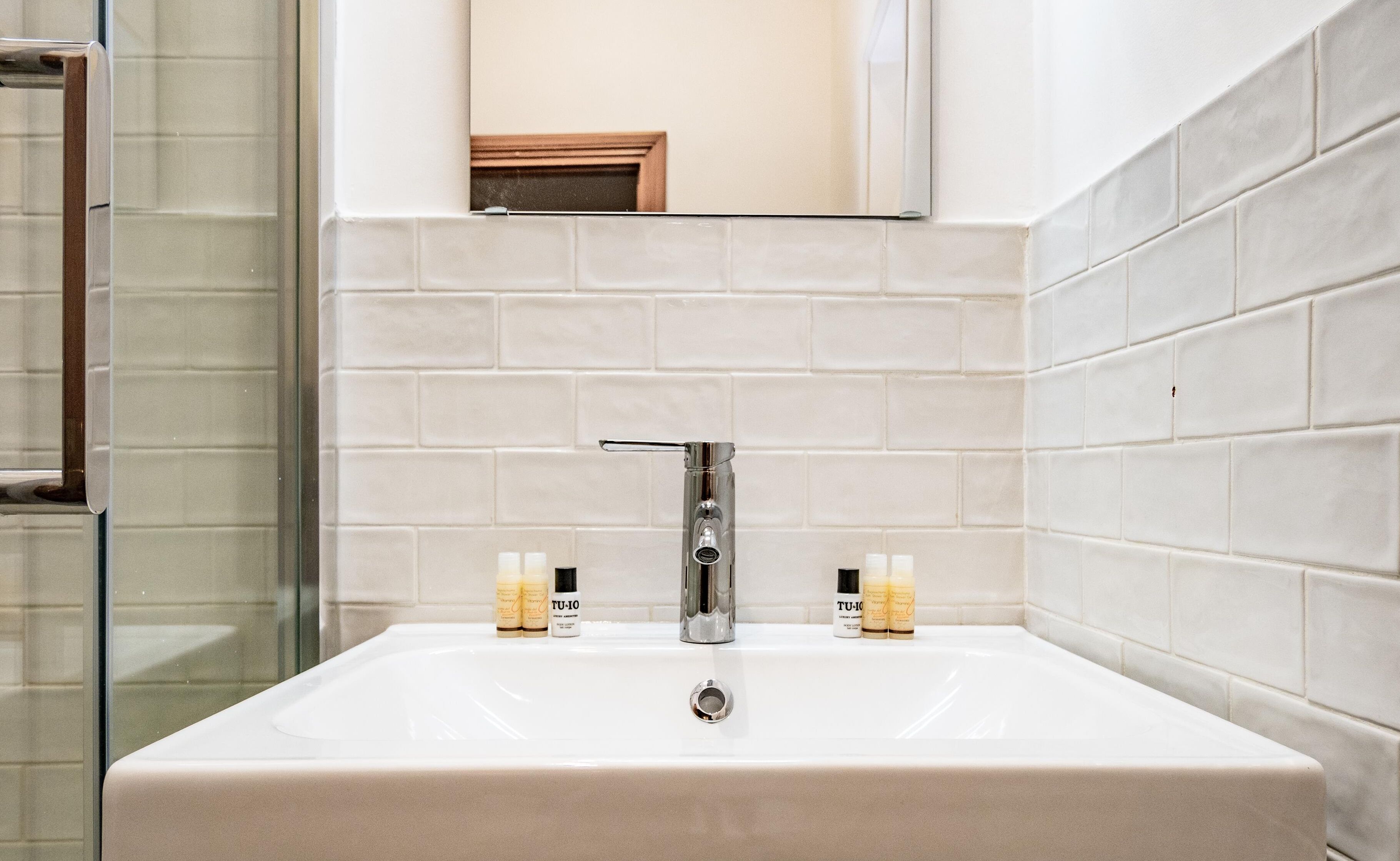 A bathroom with a white sink, two bottles of toiletries, and a mirror above the sink.