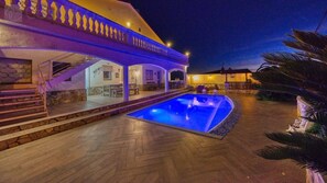 A pool area with a covered patio and a stone wall.