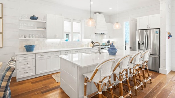 A modern kitchen with white cabinetry, a large island with bar stools, stainless steel appliances, and pendant lighting. - Steps to Beach w/ Kayak, Pool and LSV (Santa Rosa Beach)