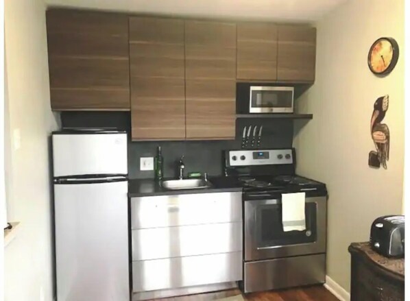 A compact kitchen with a refrigerator, stove, microwave, and a sink. - Sealy Suites - Apt  C Fully Furnished - All Bills Paid, walking distance to UTMB (Galveston)
