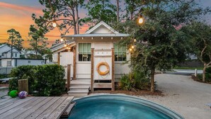 Een huis met een zwembad, houten terras en een klein veranda met lichtjes.