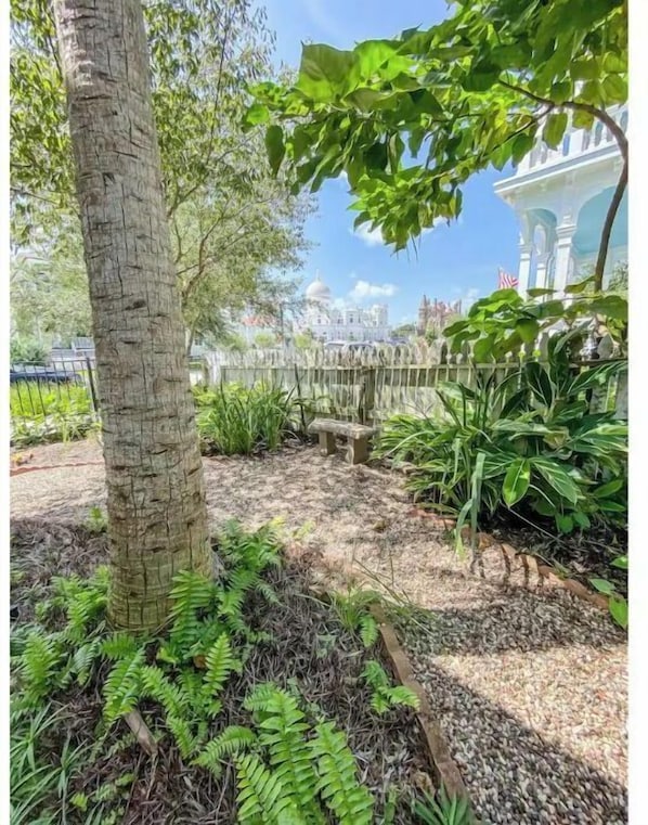 A garden with a tree, various plants, and a decorative fence.