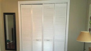 A room with a white closet, a mirror, and a lamp. - Sealy Suites D  Historic East End - Walk to Beach, UTMB & Strand  (Galveston)