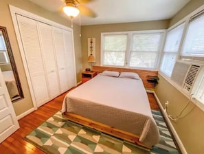 A bedroom with a bed, a nightstand, a lamp, a window, and a ceiling fan.
