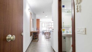 A hallway with a wooden door, a tiled floor, a dining area with chairs and a table, and a bathroom with a sink and toilet. - LA CICER BEACH APARTMENT ll (Palmas De Gran Canaria, Las)