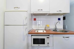 A compact kitchenette with a refrigerator, oven, and sink. - LA CICER BEACH APARTMENT ll (Palmas De Gran Canaria, Las)