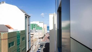 A narrow street with buildings on either side, a clear sky, and a view of the sea in the distance. - LA CICER BEACH APARTMENT ll (Palmas De Gran Canaria, Las)