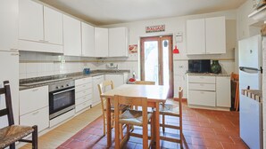 Una cucina con mobili bianchi, un tavolo da pranzo in legno e un pavimento piastrellato.