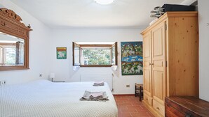 Una camera da letto con un letto grande, un armadio, una finestra vista e un quadro appeso al muro.
