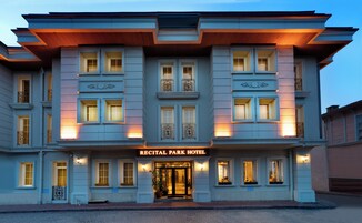 Ein mehrstöckiges Hotel mit klassischem architektonischem Design, dessen markanter Eingang eine Schilder mit der Aufschrift 'RECITAL PARK HOTEL' zeigt.