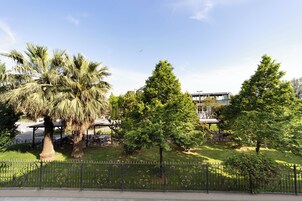 Ein Park mit Palmen, einem eingezäunten Bereich und einem Gebäude im Hintergrund.