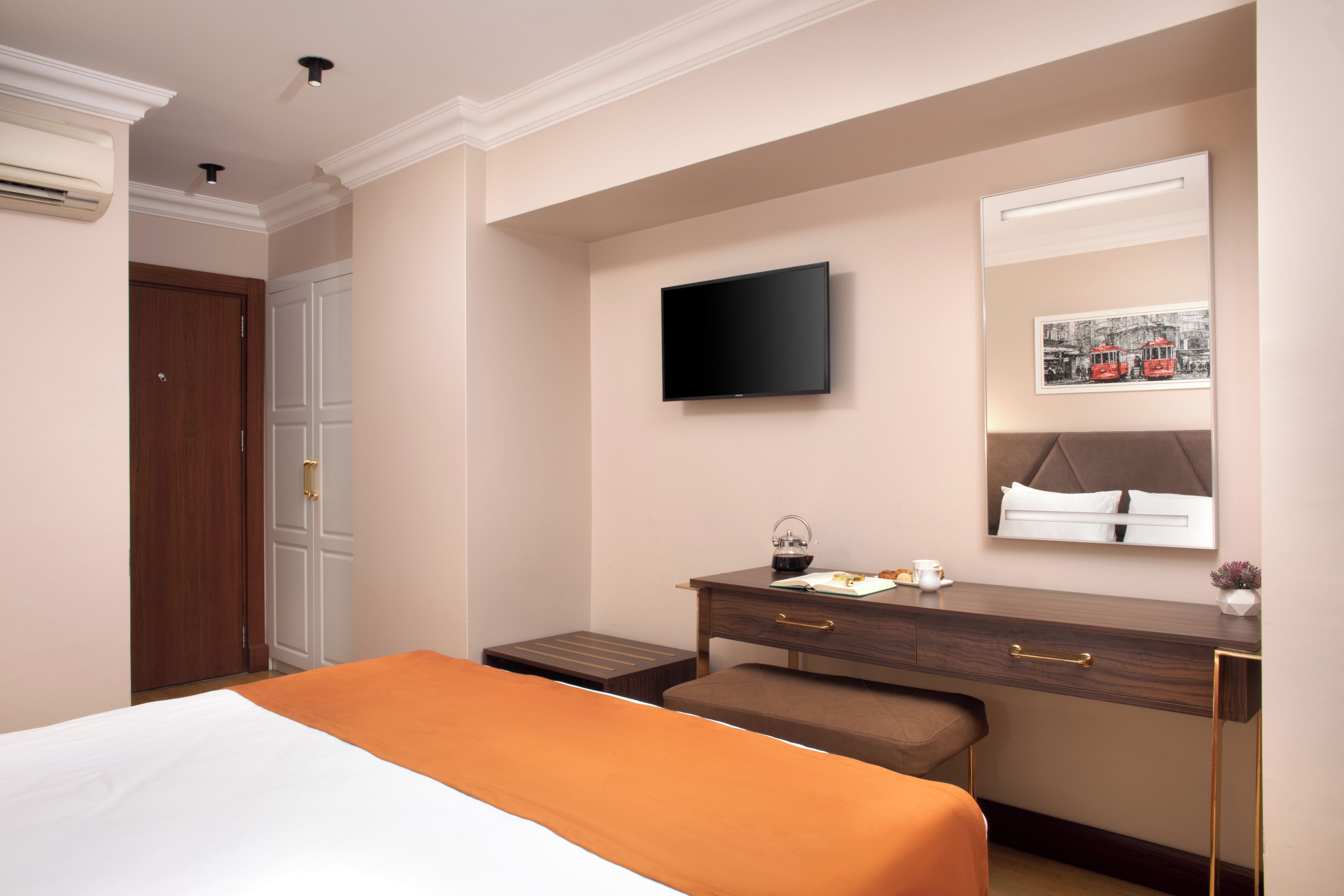 Una camera d'albergo con un letto, una scrivania con una sedia, una televisione, uno specchio e una porta.