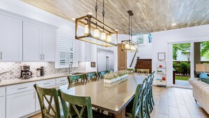 Una cucina moderna con mobili bianchi, un'isola grande con sedie e lampade a sospensione.