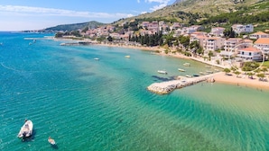 A coastal town with clear turquoise waters, a rocky pier, and buildings along the shore. - Beachfront Villa Draga with 32sqm private, heated pool, 4 bedrooms, sea view (Omis)