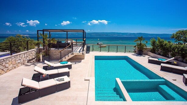 A pool area with lounge chairs and a pergola overlooking a clear blue sea. - Beachfront Villa Draga with 32sqm private, heated pool, 4 bedrooms, sea view (Omis)