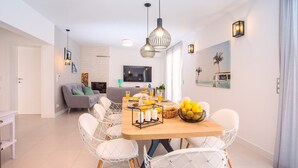 A modern living room with a dining area, featuring a wooden dining table, white wire chairs, and a grey sofa. - Beachfront Villa Draga with 32sqm private, heated pool, 4 bedrooms, sea view (Omis)