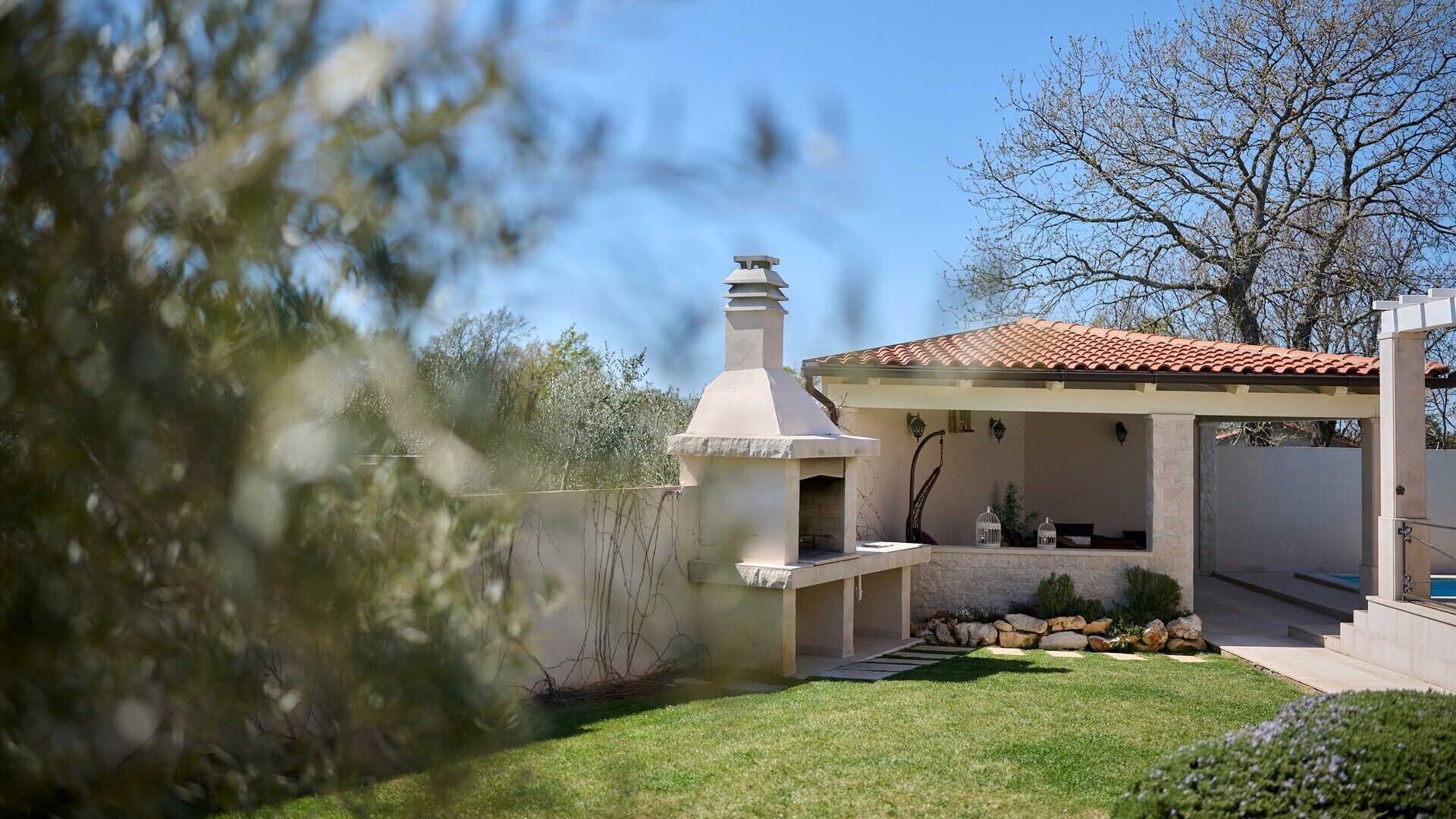 A patio with a barbecue grill, a covered seating area, and a pool.