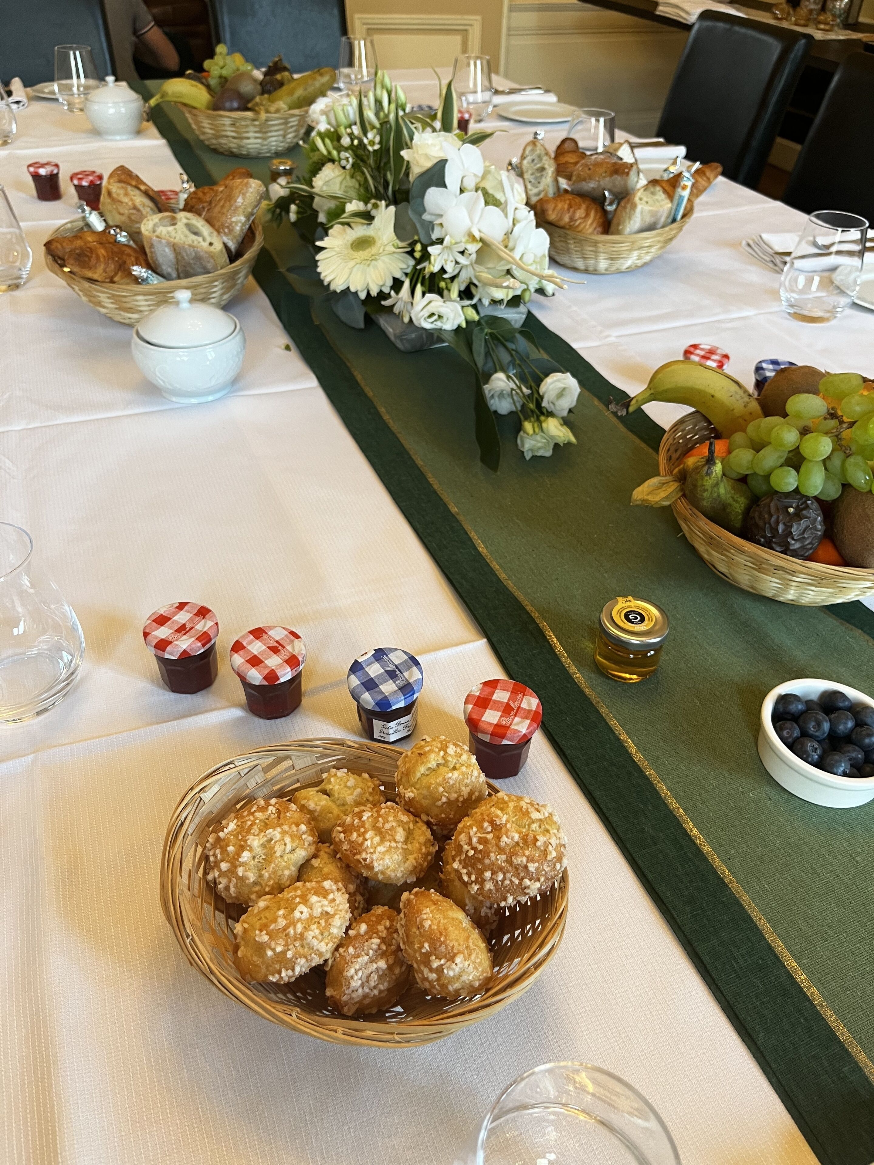 A table set for a meal with bread, flowers, and fruit baskets.