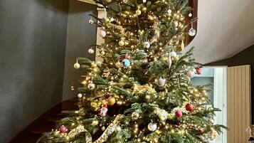 Un árbol de Navidad decorado en una habitación con una escalera y alfombra estampada.