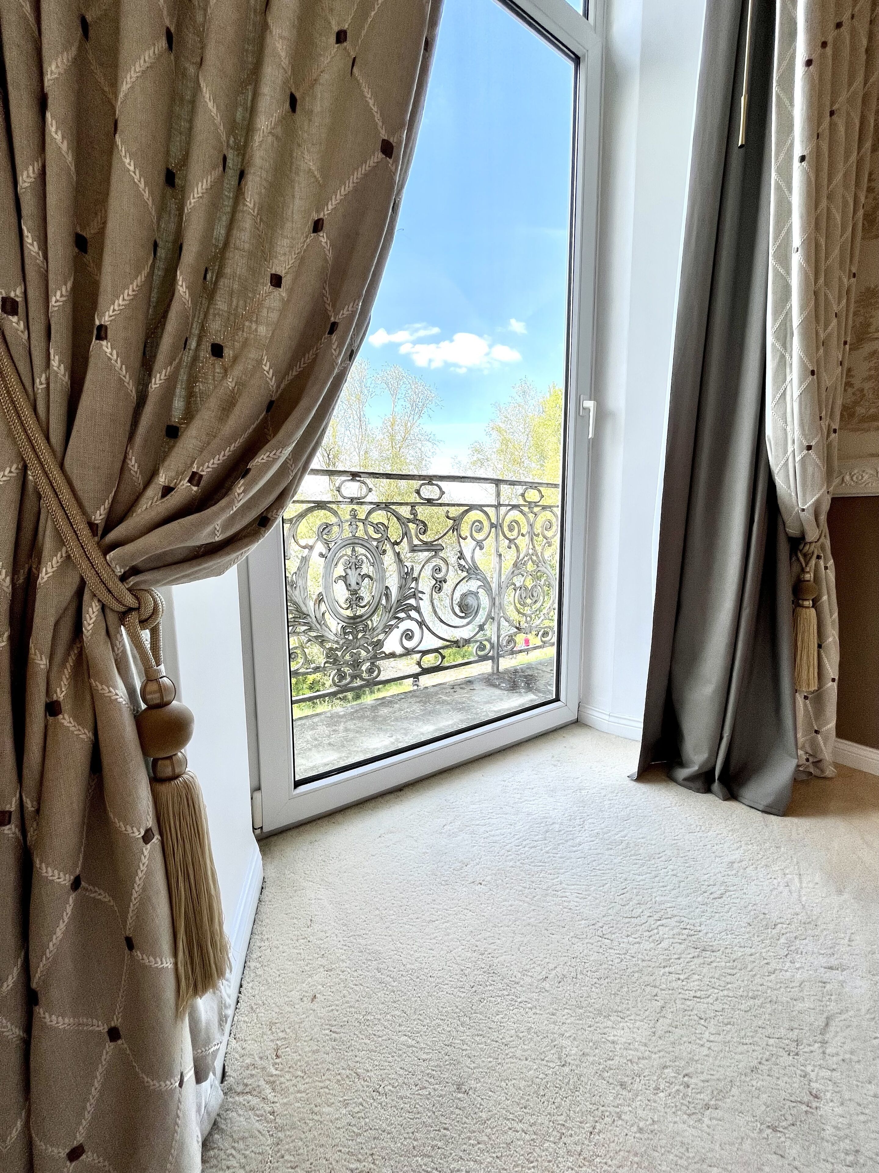 Une pièce dotée d’une grande porte-fenêtre coulissante donnant sur un balcon agrémenté de garde-corps en métal ouvragé.
