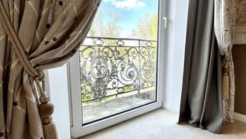 Une pièce dotée d’une grande porte-fenêtre coulissante donnant sur un balcon agrémenté de garde-corps en métal ouvragé.